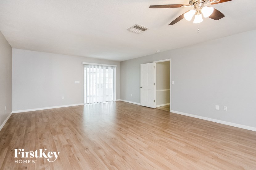 an empty living room with wood flooring and a ceiling fan
