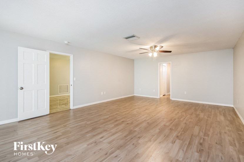 an empty living room with wood flooring and a ceiling fan