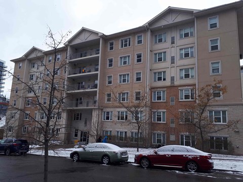 an apartment building with cars parked outside in the snow