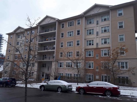 Two cars are parked in a parking lot in front of a large apartment building.