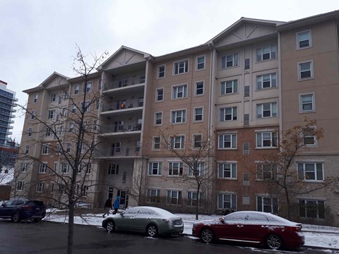 an apartment building with cars parked outside in the snow