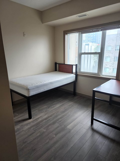 A bedroom with a bed, a table and a window.