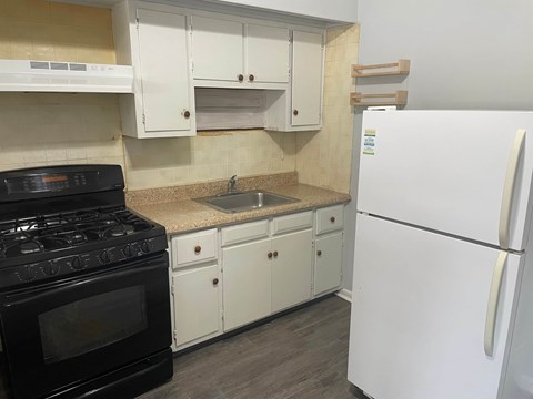 A kitchen with a black stove top oven, white cabinets, and a white refrigerator.