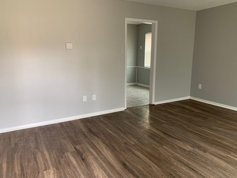 a living room with wood floors and a door to a hallway