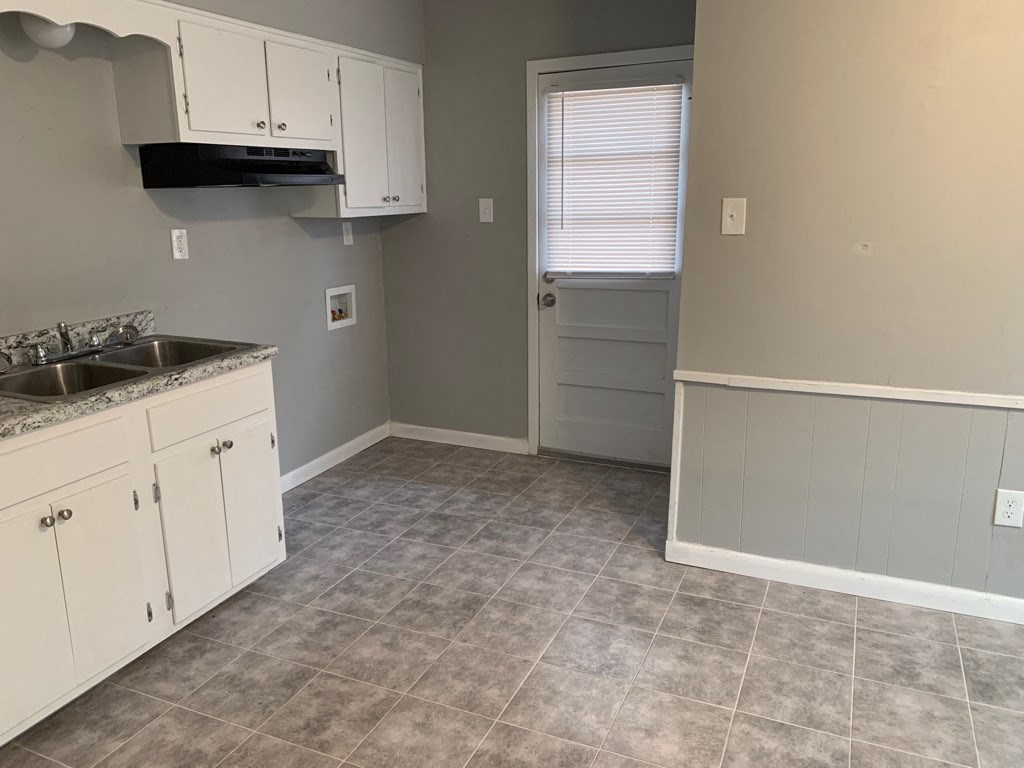 an empty kitchen with white cabinets and a sink