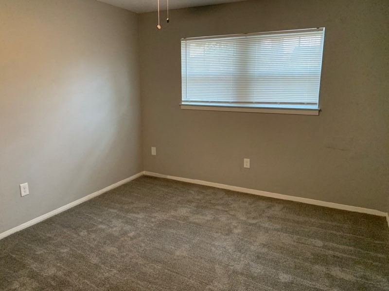an empty room with a window and a carpeted floor