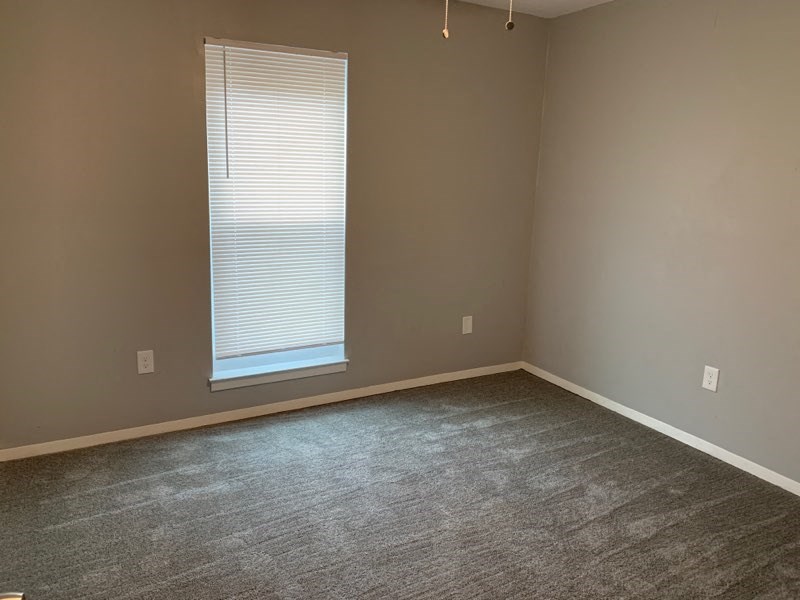 an empty room with a window and a carpet