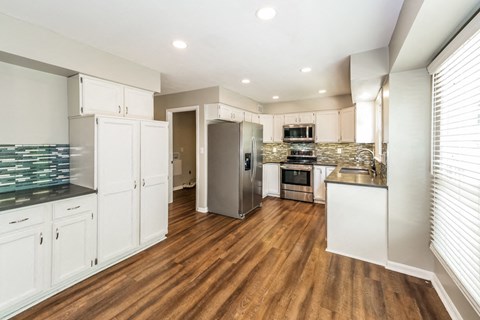 a large kitchen with white cabinets and a stainless steel refrigerator