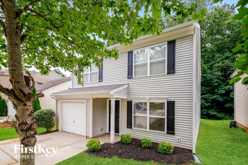a white house with black shutters and a tree in the yard