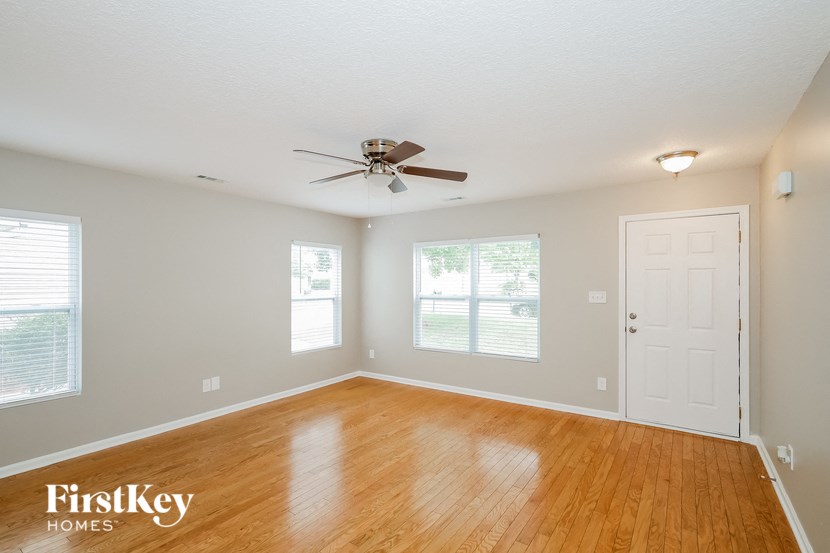 an empty living room with a ceiling fan and a door