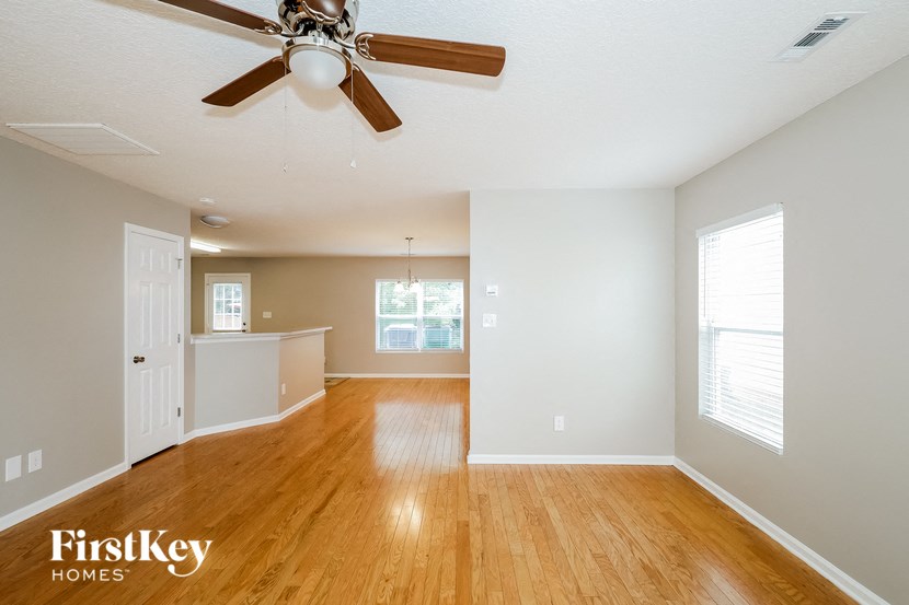 an empty living room and kitchen with a ceiling fan