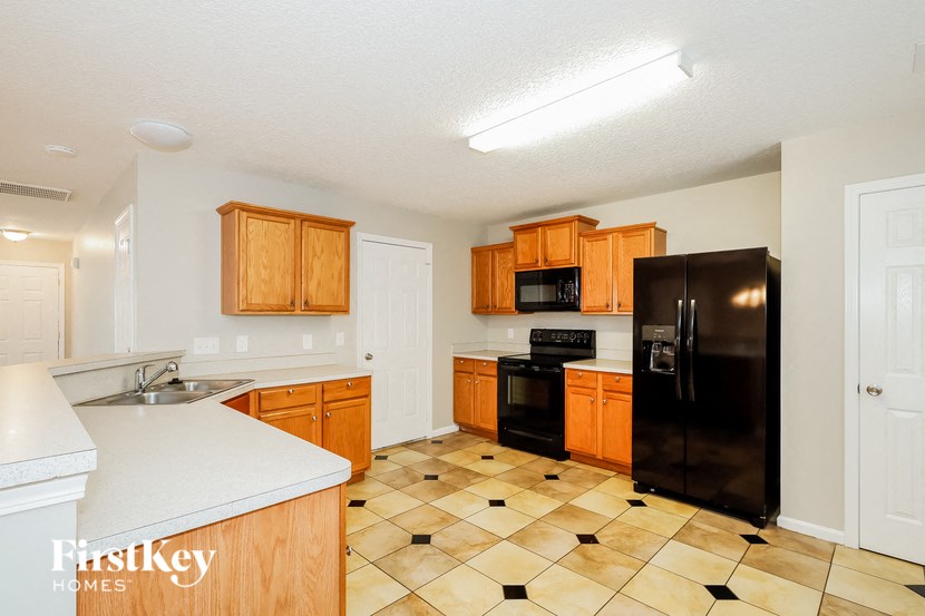 a kitchen with wooden cabinets and a black refrigerator