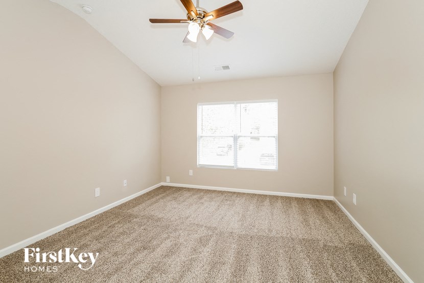 an empty room with a ceiling fan and a window