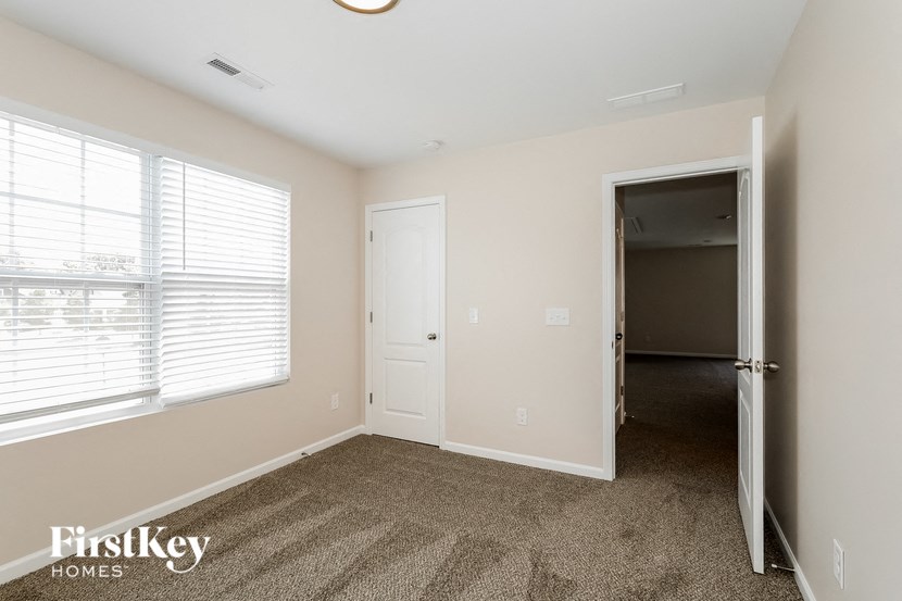 a bedroom with a door to a hallway and a large window