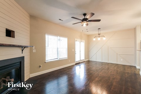 A spacious room with a fireplace and wooden flooring.