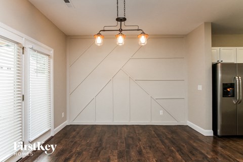 A kitchen with a stainless steel refrigerator and wooden flooring.