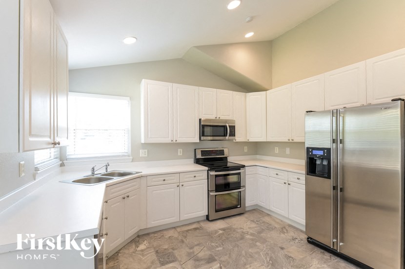 a white kitchen with stainless steel appliances and white cabinets