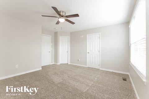 a spacious living room with carpet and a ceiling fan