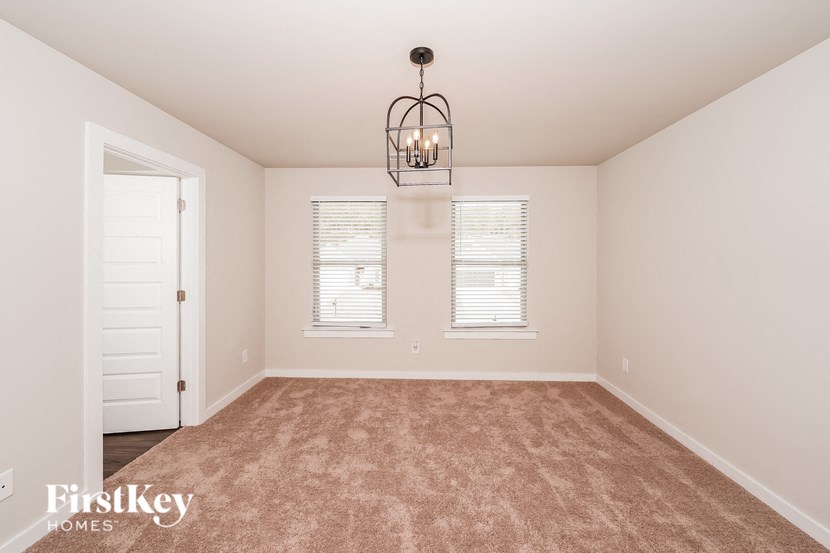 A room with a carpeted floor and a chandelier hanging from the ceiling.