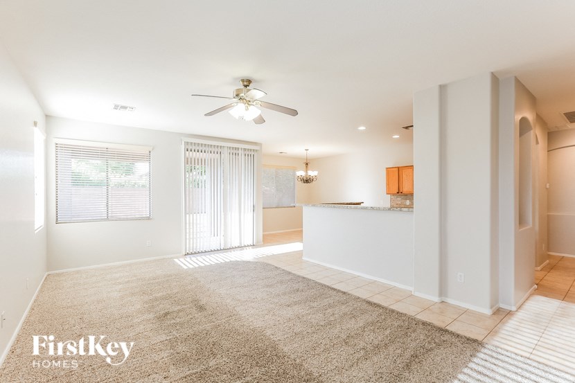 A spacious living room with a carpeted floor and a ceiling fan.