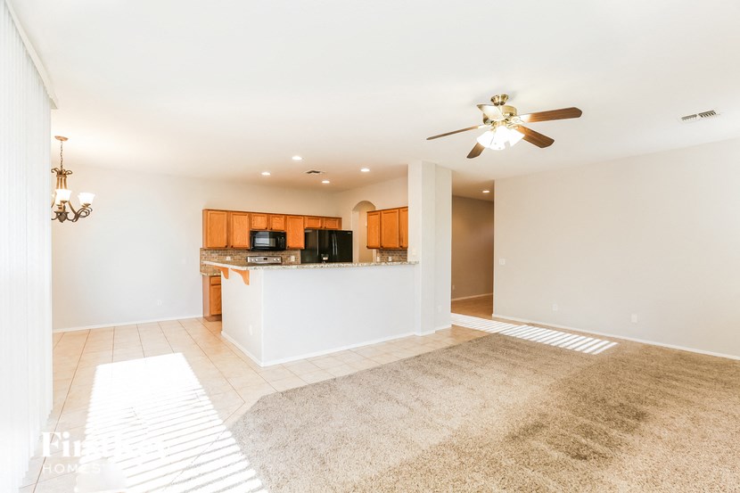 A spacious living room with a bar area and a ceiling fan.