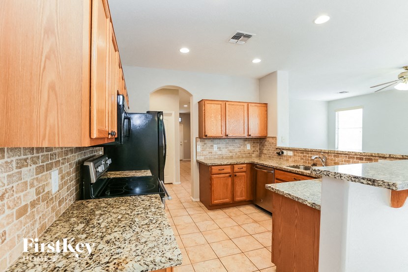 A kitchen with a black refrigerator and wooden cabinets.