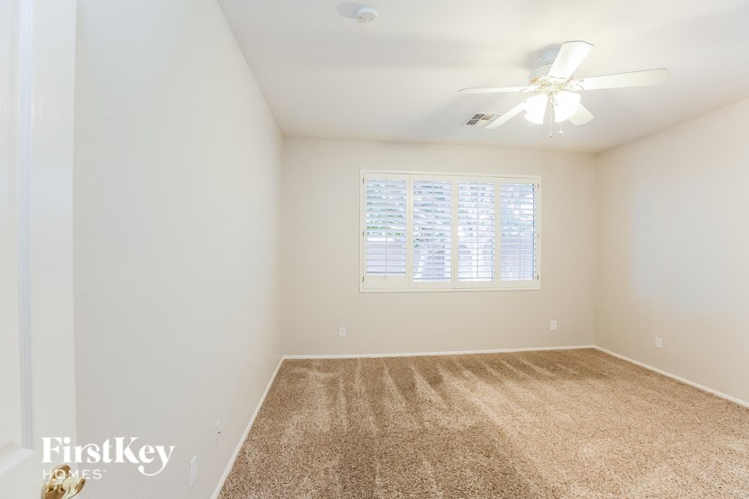 A room with a carpeted floor and a ceiling fan.