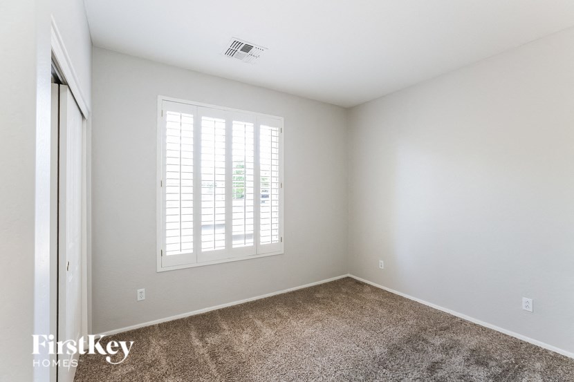 A room with a carpeted floor and a window with blinds.