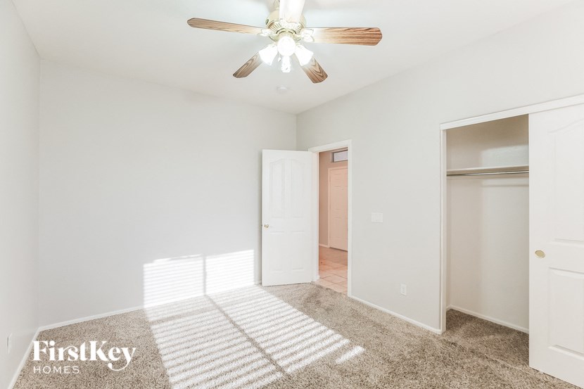 A room with a ceiling fan and a rug on the floor.