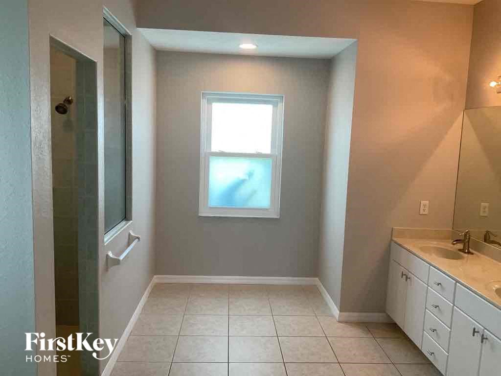 A bathroom with a window, sink, and mirror.