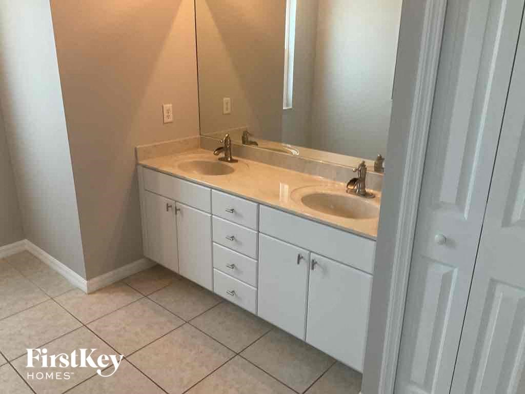 A bathroom with a white sink and cabinets.