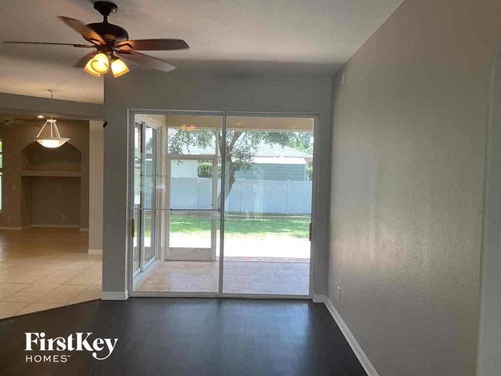A room with a ceiling fan and sliding glass doors leading to a backyard.