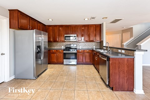 A kitchen with wooden cabinets and a tile floor.