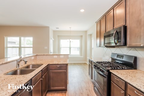 A kitchen with brown cabinets and a black stove top oven.