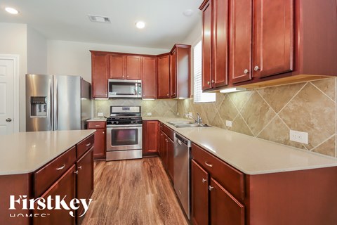 A kitchen with wooden cabinets and a stainless steel refrigerator.