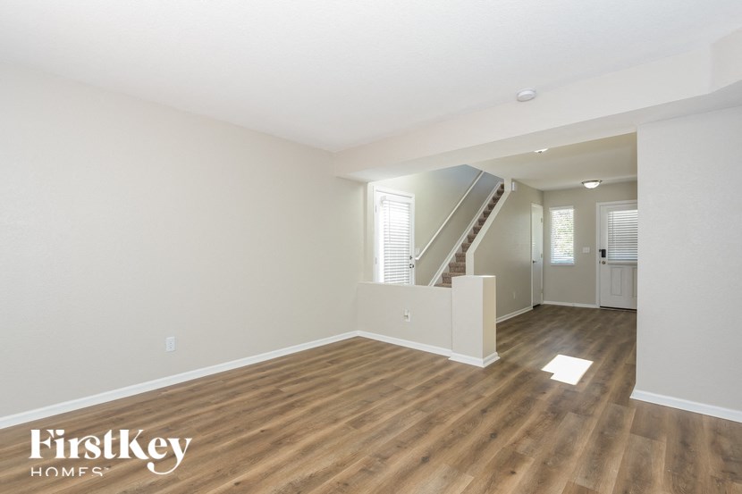 A spacious room with wooden floors and a staircase leading to another room.