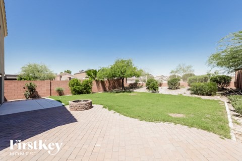 A backyard with a brick patio and a pool.