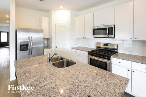 a white kitchen with granite counter tops and stainless steel appliances