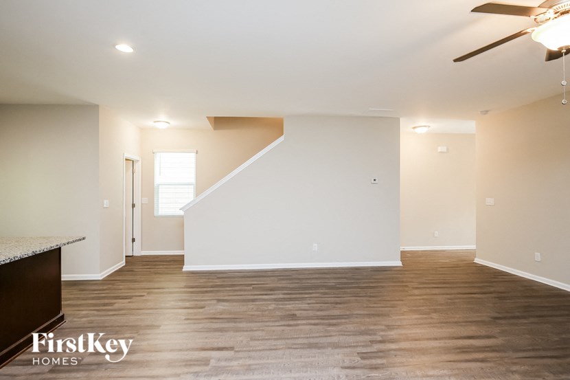 a living room with white walls and wood flooring and a ceiling fan