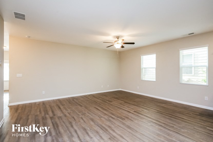 the spacious living room with wood flooring and a ceiling fan