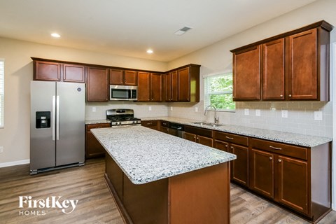 a kitchen with wooden cabinets and granite counter tops and a stainless steel refrigerator