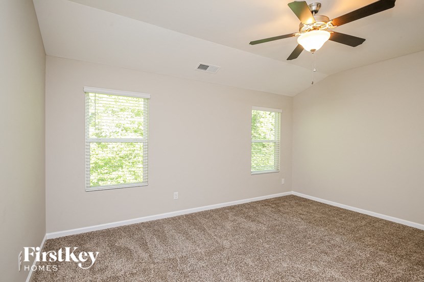 the master bedroom has a carpeted floor and a ceiling fan