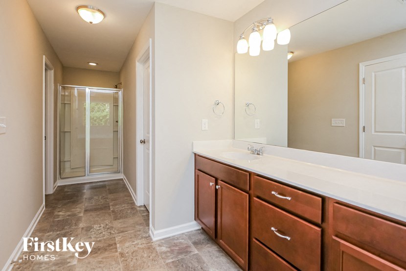 the master bathroom has a large vanity and a walk in shower