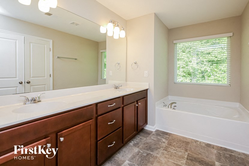 a bathroom with two sinks and a tub and a window