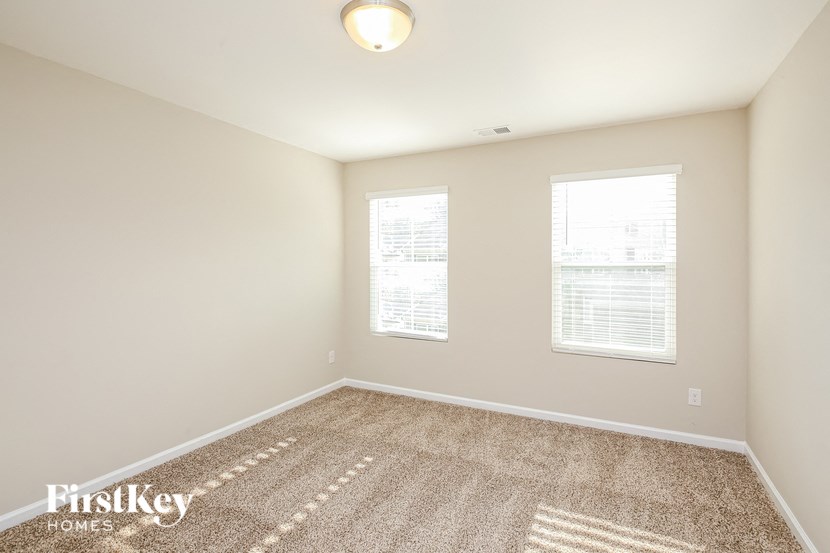 a spacious room with carpet and two windows