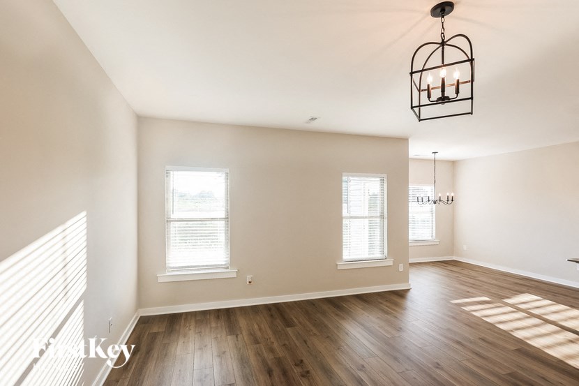 the living room and dining room with wood floors and a chandelier