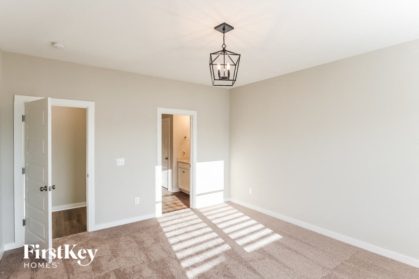 an empty living room with a light fixture and carpet