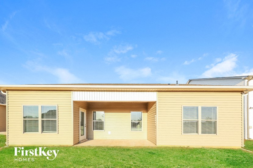 the front of a yellow house with a green lawn