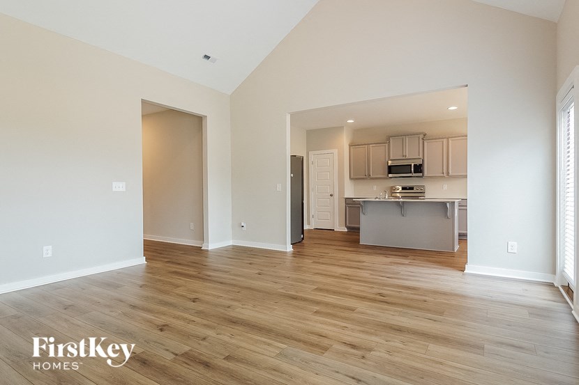an empty living room and kitchen with wood flooring