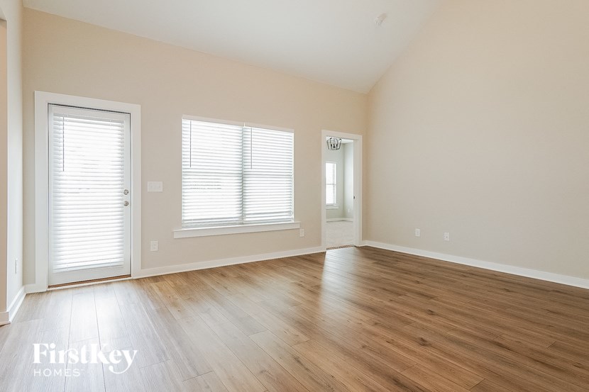 an empty living room with wood floors and a door and window